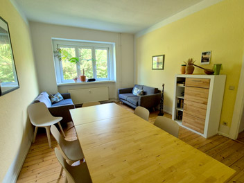 Wohnraum mit Tisch, Fenster, Regalen, Büchern