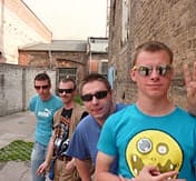 Vier junge Männer mit Sonnenbrillen stehen hintereinander in einer Einfahrt